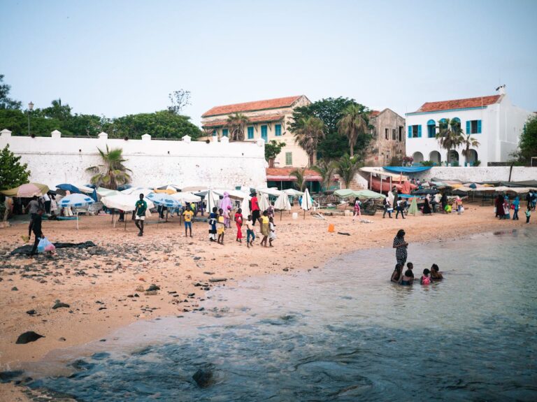 Lively beach scene with people enjoying the coastline near historic buildings.